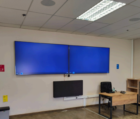 Sala de capacitación corporativa equipada con pantallas, sistema de audio y presentación integrada por Qualis AV